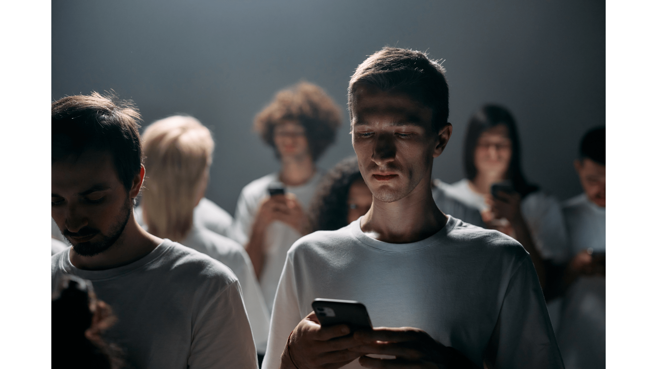 Un grup de oameni care se holbează la telefoane. Imaginea are tonuri gri-albăstrui.